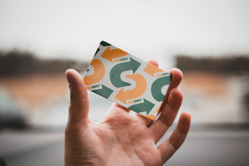 person holding green and white subway card