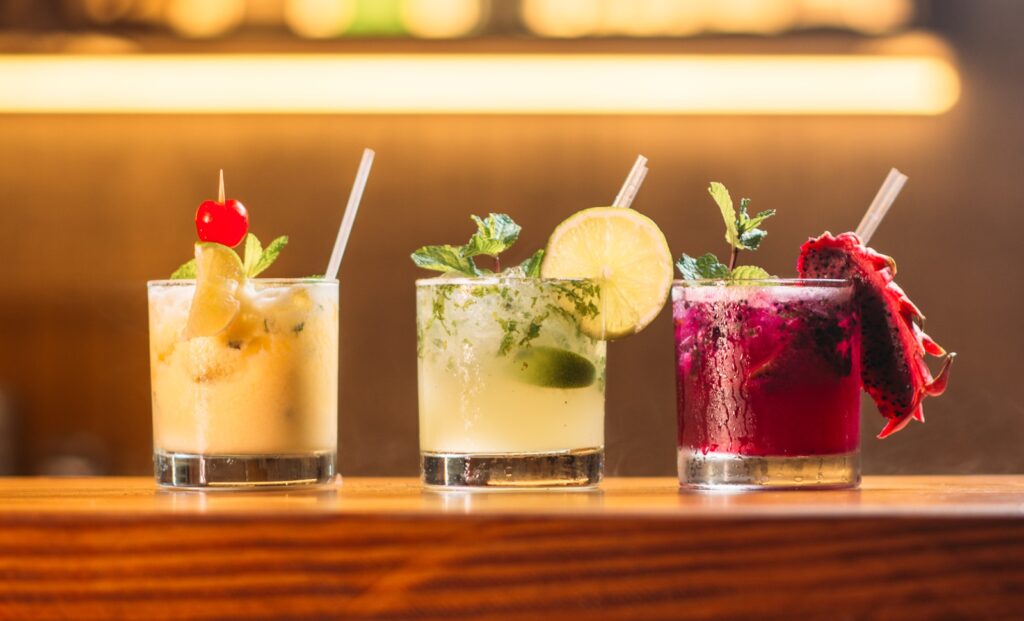 three clear glass cups with juice at a bar