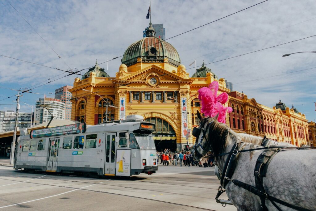 white tram near flinders street station brown and yellow dome building